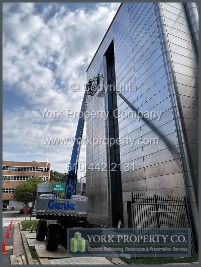 Company near me restoring scratched exterior stainless steel building facade clad panels.