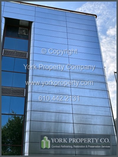 Company restoring scarred stainless steel building facade exterior clad panels.