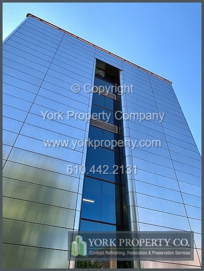 Cleaning scratched stainless steel clad building facade panels.