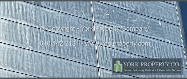 Professional company repairing damaged exterior stainless steel building facade panels.