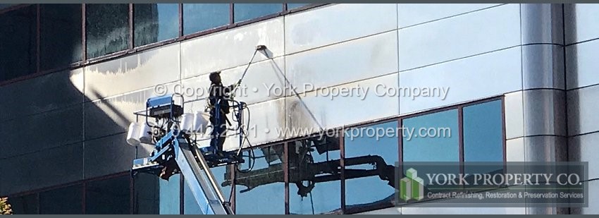 Company cleaning caulking stained stainless steel building facade paneling.