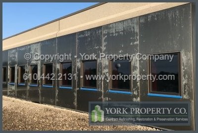 Company stripping peeling lacquer off of anodized aluminum building facade panels.