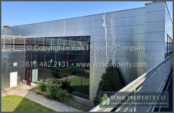 Local company cleaning dirty stainless steel exterior siding panels.