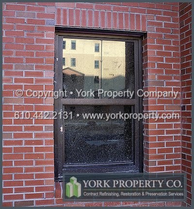 Cleaning concrete off of bronze anodized aluminum window frames.